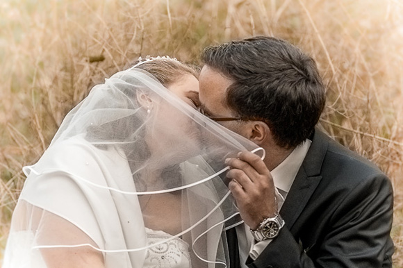 Foto Hochzeit Brautpaar im Park Kuss Schleier